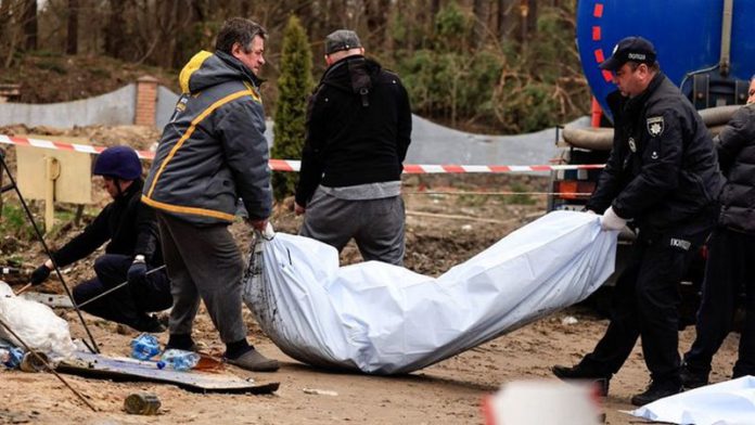 Police members carry the body of a civilian, after they exhumed him along with another body from a well at the fuel station in Buzova (Image: REUTERS)