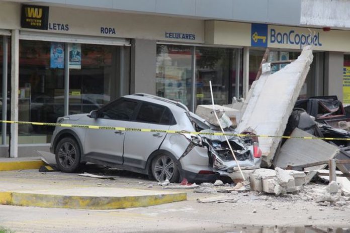 A vehicle smashed by the falling façade of a department store ( Image: REUTERS)