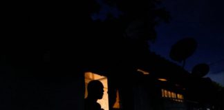 A man looks out from a window while talking to a person during the power cut in Colombo, Sri Lanka March 30, 2022. REUTERS/Dinuka Liyanawatte