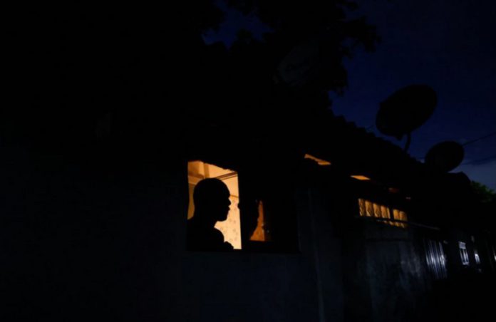 A man looks out from a window while talking to a person during the power cut in Colombo, Sri Lanka March 30, 2022. REUTERS/Dinuka Liyanawatte