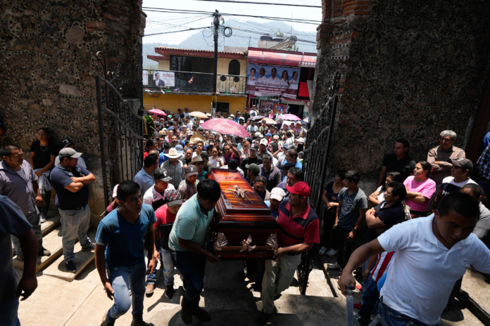 People carry a coffin that contains the remains of a man slain in a mass shooting into a church for a funeral service in Huitzilac, Mexico, on May 14. Fernando Llano/AP