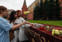 EPA/ People lay flowers as tribute to the victims of Sunday's attack on a memorial bearing the word Sevastopol in Moscow