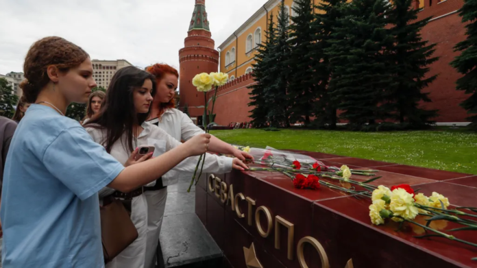 EPA/ People lay flowers as tribute to the victims of Sunday's attack on a memorial bearing the word Sevastopol in Moscow