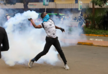 A protester throws a tear gas canister back at police officers during a protest over proposed tax hikes in Nairobi, Kenya on June 20, 2024 [Andrew Kasuku/AP]