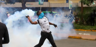 A protester throws a tear gas canister back at police officers during a protest over proposed tax hikes in Nairobi, Kenya on June 20, 2024 [Andrew Kasuku/AP]